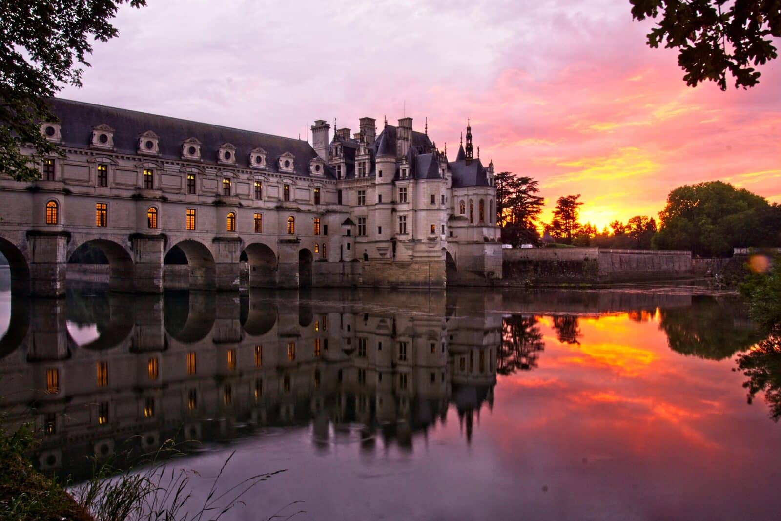 Vue du château de Chenonceau se reflétant dans le Cher, en Val de Loire, au coucher du soleil
